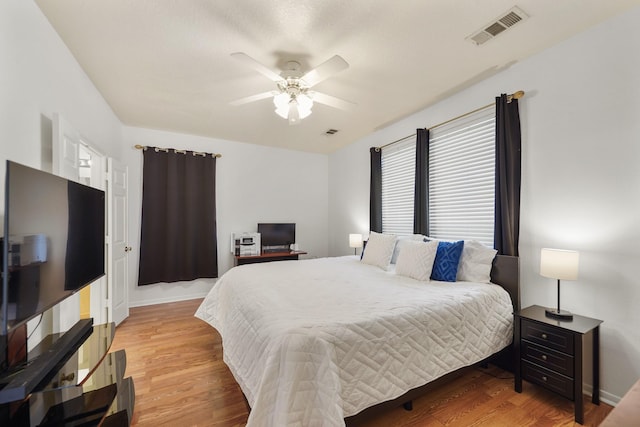 bedroom with light wood-type flooring, visible vents, baseboards, and ceiling fan