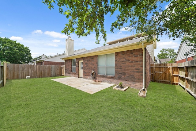rear view of property featuring a chimney, a patio, brick siding, and a fenced backyard