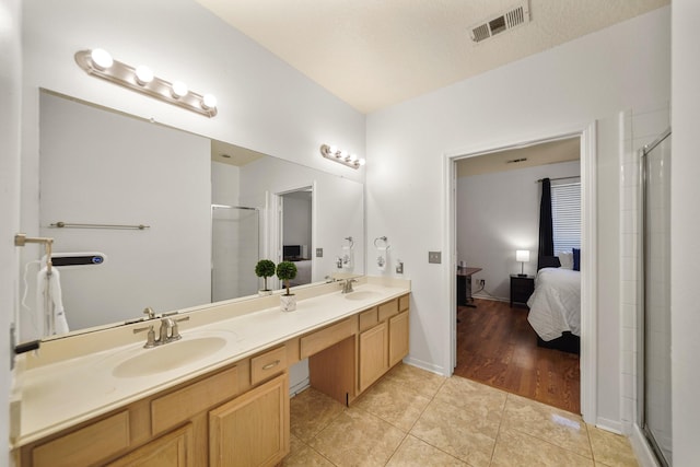 bathroom featuring a shower stall, visible vents, a sink, and double vanity