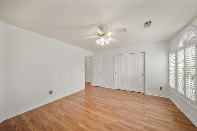 unfurnished bedroom with a closet, visible vents, ceiling fan, light wood-style flooring, and baseboards