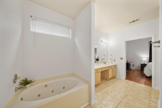 bathroom with connected bathroom, a tub with jets, tile patterned floors, visible vents, and vanity
