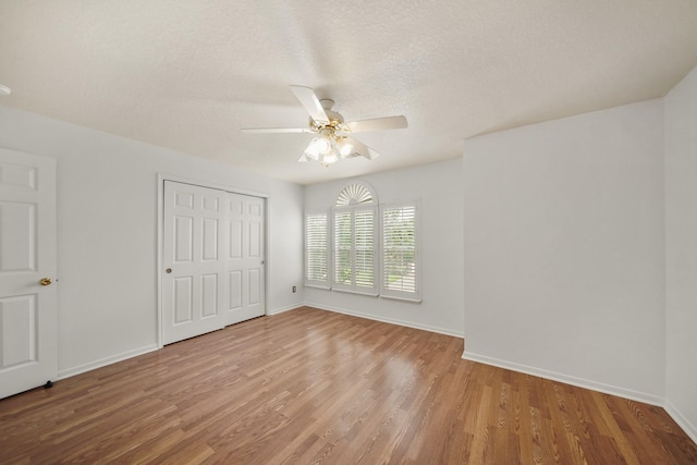 unfurnished bedroom with wood finished floors, a ceiling fan, a closet, a textured ceiling, and baseboards