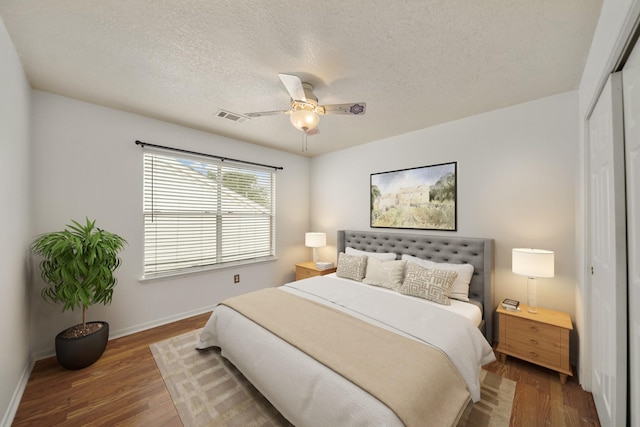 bedroom with wood finished floors, a ceiling fan, a closet, visible vents, and baseboards