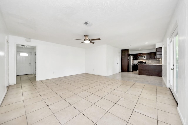 unfurnished living room featuring a ceiling fan, recessed lighting, a sink, and light tile patterned floors