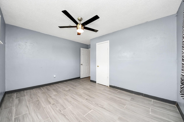 empty room with a ceiling fan, wood tiled floors, baseboards, and a textured ceiling
