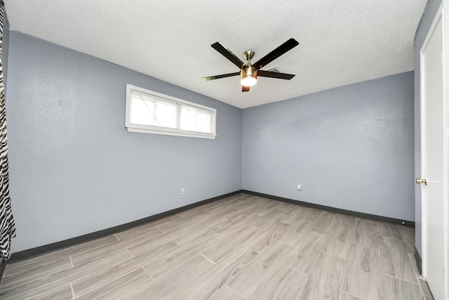 empty room featuring ceiling fan, light wood-type flooring, baseboards, and a textured ceiling
