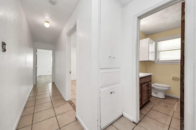 corridor with light tile patterned flooring and baseboards