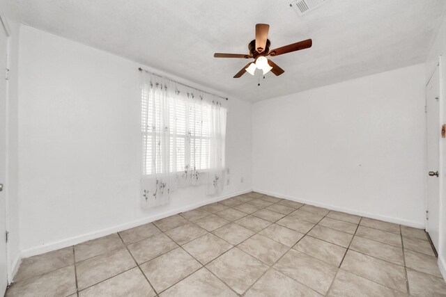 empty room with a ceiling fan, baseboards, and light tile patterned floors