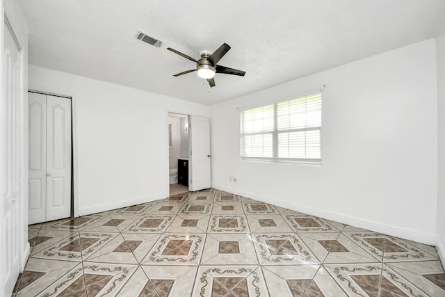 unfurnished bedroom featuring a closet, light tile patterned floors, baseboards, and ceiling fan