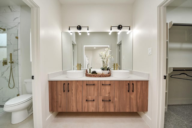 full bath featuring a marble finish shower, double vanity, and toilet
