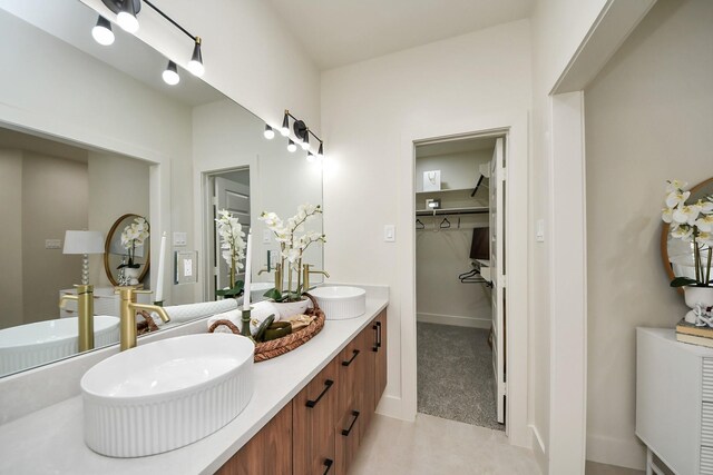 full bathroom with a walk in closet and double vanity