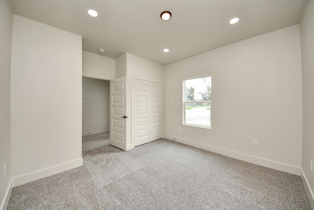 unfurnished bedroom featuring light colored carpet, recessed lighting, baseboards, and a closet