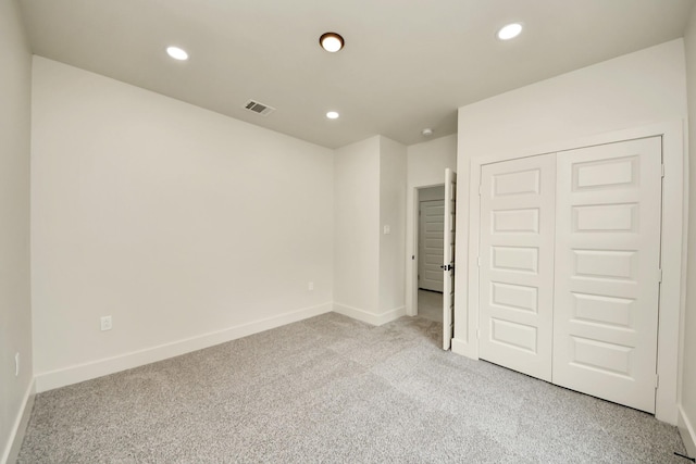 unfurnished bedroom featuring light carpet, recessed lighting, baseboards, and a closet