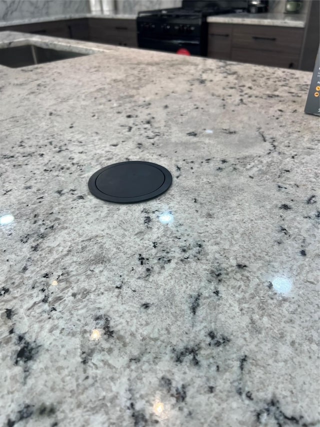 kitchen view of black range with gas stovetop and light stone counters