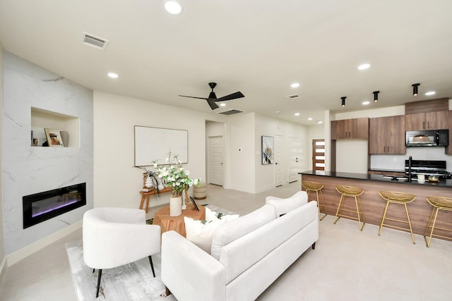 living area with recessed lighting, a ceiling fan, a high end fireplace, and baseboards