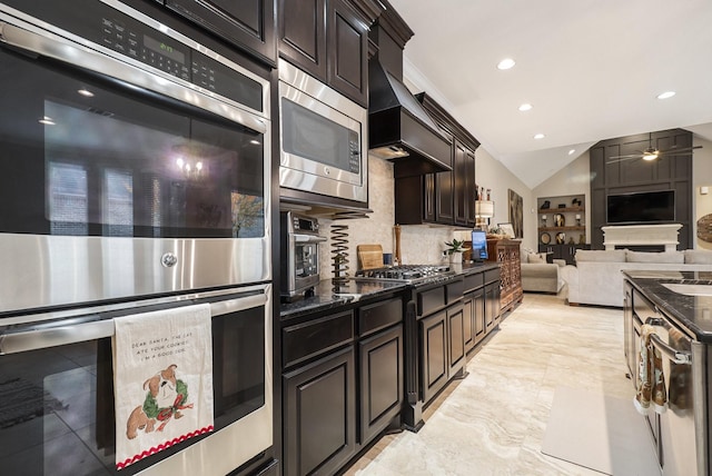 kitchen with vaulted ceiling, dark stone countertops, a ceiling fan, and appliances with stainless steel finishes