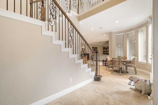 interior space with recessed lighting, baseboards, a high ceiling, and stairs