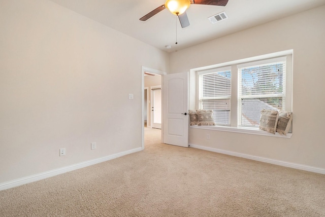 spare room with ceiling fan, light carpet, baseboards, and visible vents