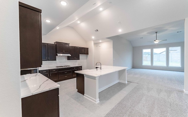 21215 Brook Tide Ln, Cypress, TX 77433 - kitchen featuring a sink, light stone countertops, under cabinet range hood, gas cooktop, and lofted ceiling