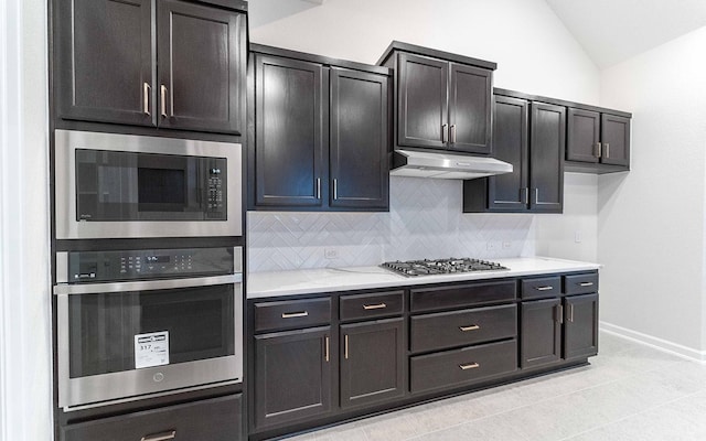 21215 Brook Tide Ln, Cypress, TX 77433 - kitchen featuring tasteful backsplash, vaulted ceiling, under cabinet range hood, light tile patterned floors, and appliances with stainless steel finishes
