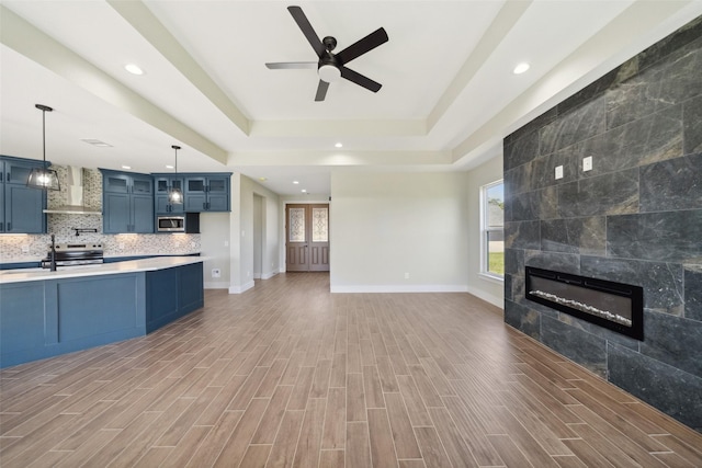 237 Crestview Dr, West Columbia, TX 77486 - unfurnished living room featuring a tray ceiling, a fireplace, a ceiling fan, and a healthy amount of sunlight