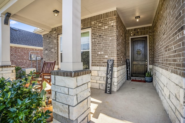 view of exterior entry with a porch and brick siding