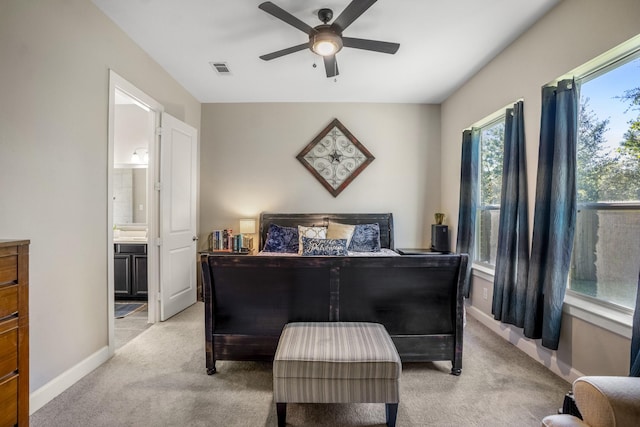 bedroom featuring a ceiling fan, visible vents, baseboards, ensuite bath, and light carpet