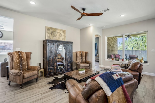 living area with a ceiling fan, wood tiled floor, recessed lighting, visible vents, and arched walkways