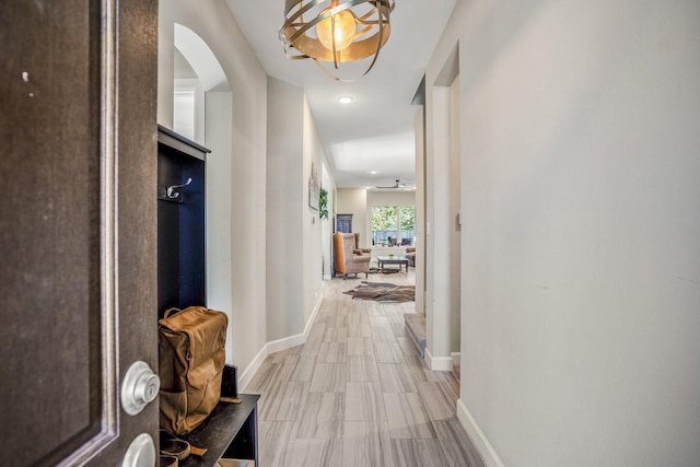 corridor with baseboards, arched walkways, and recessed lighting