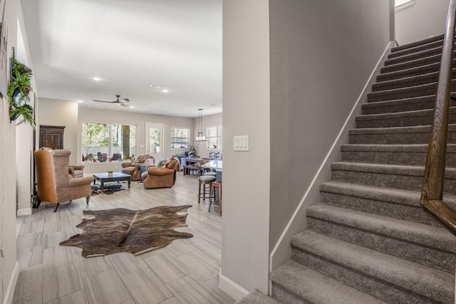 staircase featuring ceiling fan, baseboards, and recessed lighting