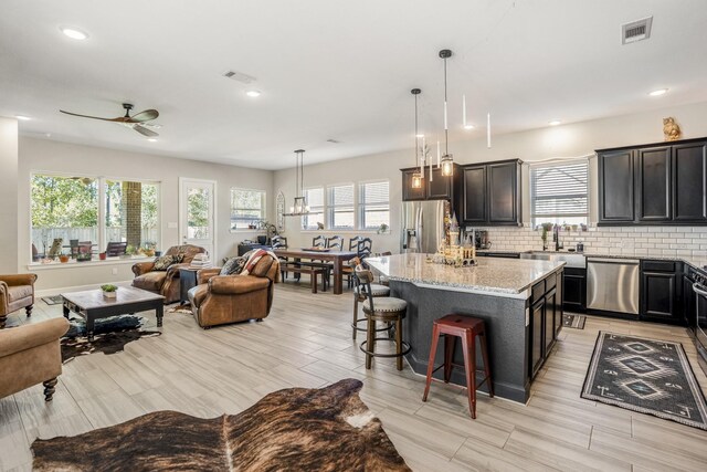 kitchen featuring a center island, a sink, open floor plan, visible vents, and appliances with stainless steel finishes