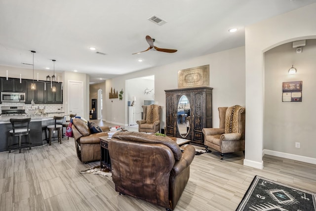 living area with ceiling fan, arched walkways, baseboards, and visible vents