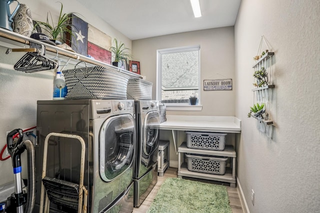 washroom with baseboards, washer and dryer, wood finished floors, laundry area, and a textured wall