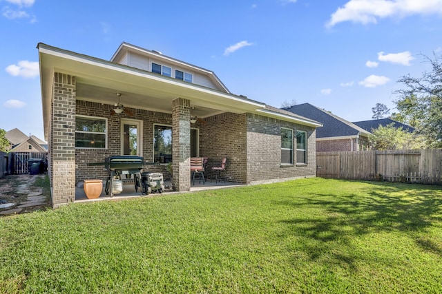 rear view of property with a patio, a ceiling fan, a fenced backyard, a yard, and brick siding