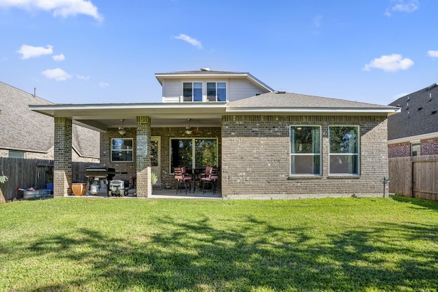 rear view of house with a yard, brick siding, ceiling fan, a patio area, and a fenced backyard