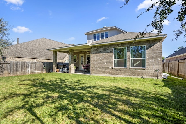 rear view of house with a yard, brick siding, a fenced backyard, and a patio