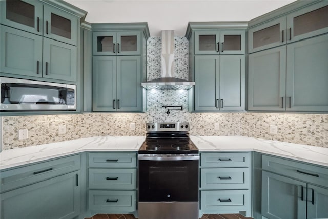 443 Wellshire Dr, West Columbia, TX 77486 - kitchen with backsplash, wall chimney range hood, stainless steel appliances, and light stone countertops
