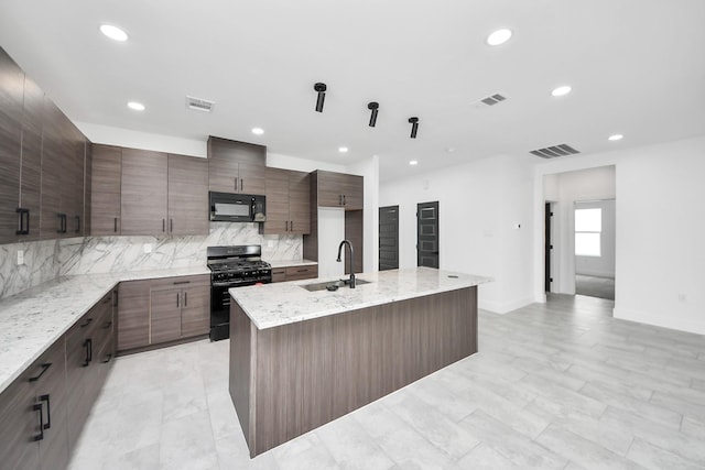 kitchen featuring black microwave, range with gas cooktop, a sink, tasteful backsplash, and recessed lighting