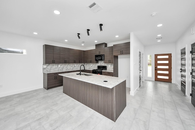 kitchen featuring black appliances, a sink, recessed lighting, decorative backsplash, and an island with sink