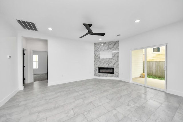unfurnished living room featuring ceiling fan, recessed lighting, a high end fireplace, baseboards, and light marble finish flooring
