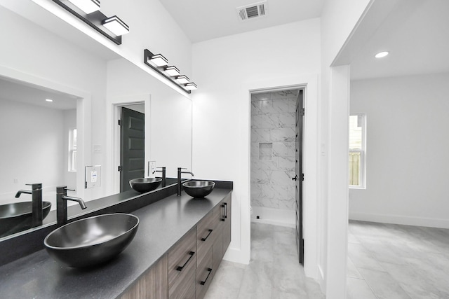 bathroom featuring marble look tiles, a marble finish shower, double vanity, recessed lighting, and baseboards