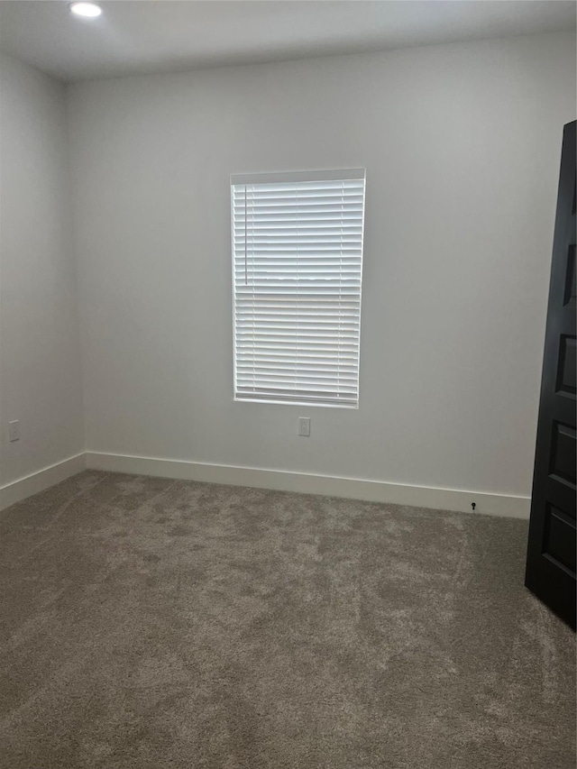carpeted spare room featuring baseboards