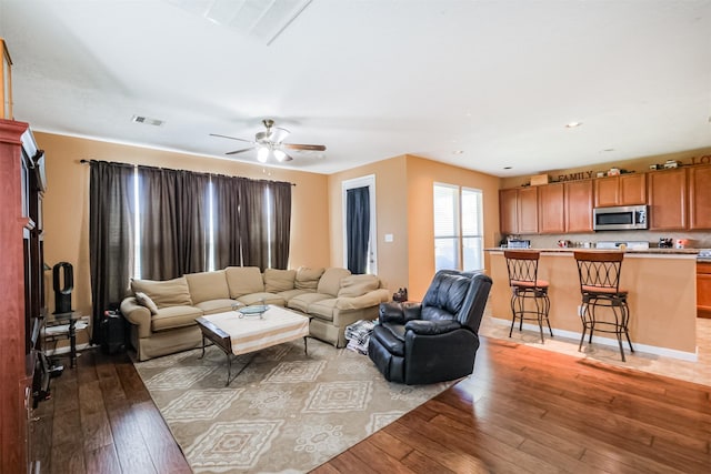 living room with light wood finished floors, ceiling fan, and visible vents