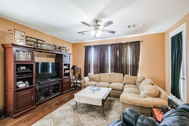 living room featuring dark wood-style flooring, ceiling fan, and visible vents