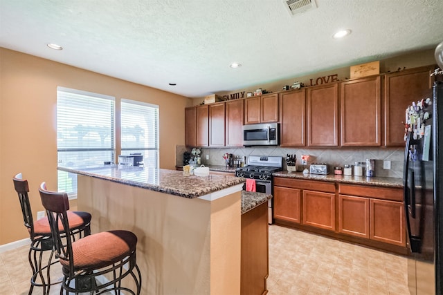 kitchen with a wealth of natural light, visible vents, appliances with stainless steel finishes, and a breakfast bar
