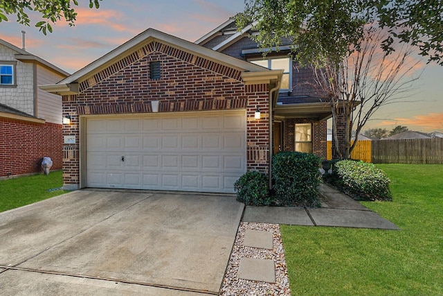 view of front of property featuring driveway, brick siding, fence, a garage, and a front yard