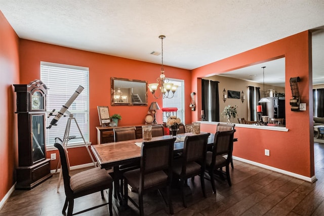 dining area featuring baseboards, dark wood finished floors, an inviting chandelier, and visible vents