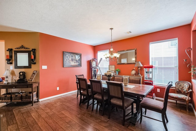 dining space featuring baseboards, a notable chandelier, dark wood-type flooring, and visible vents