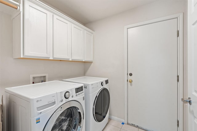 clothes washing area with cabinet space, light tile patterned floors, and washer and dryer