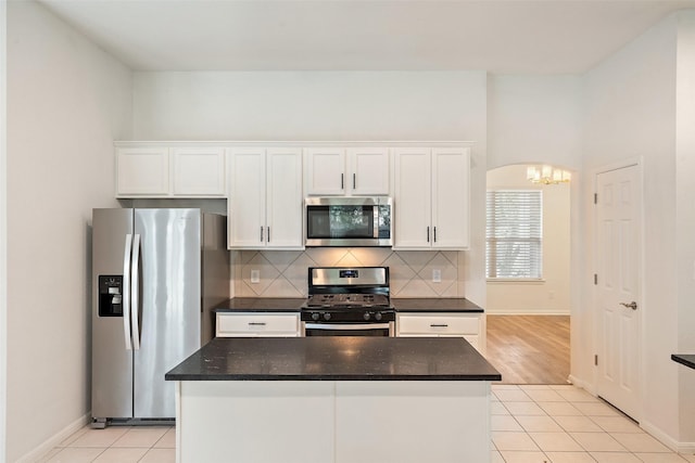 kitchen with light tile patterned floors, white cabinets, baseboards, appliances with stainless steel finishes, and tasteful backsplash